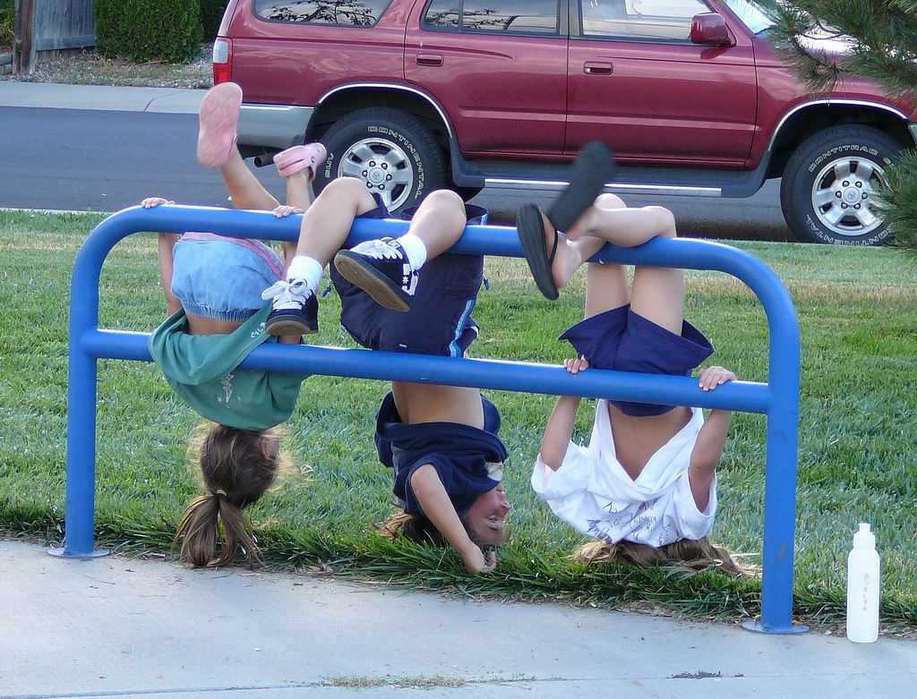 children hanging upside from fence